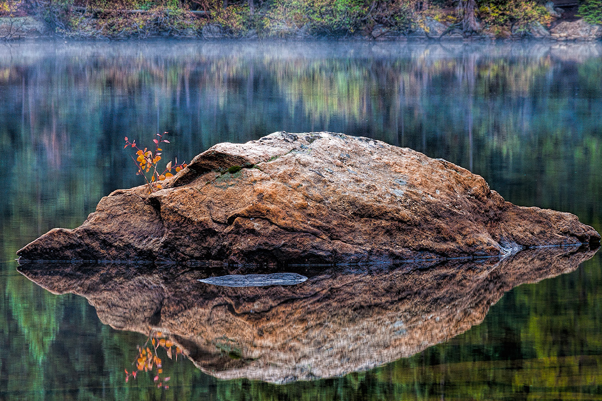 On a very calm evening a rocks reflects on Bear Lake.