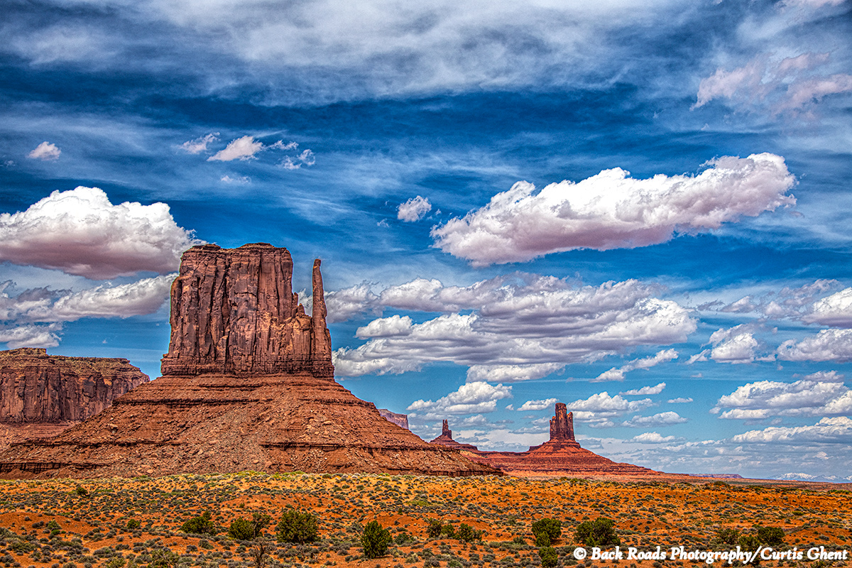 Blu skies, puffy white clouds highlight the mittens in Monument Valley.
